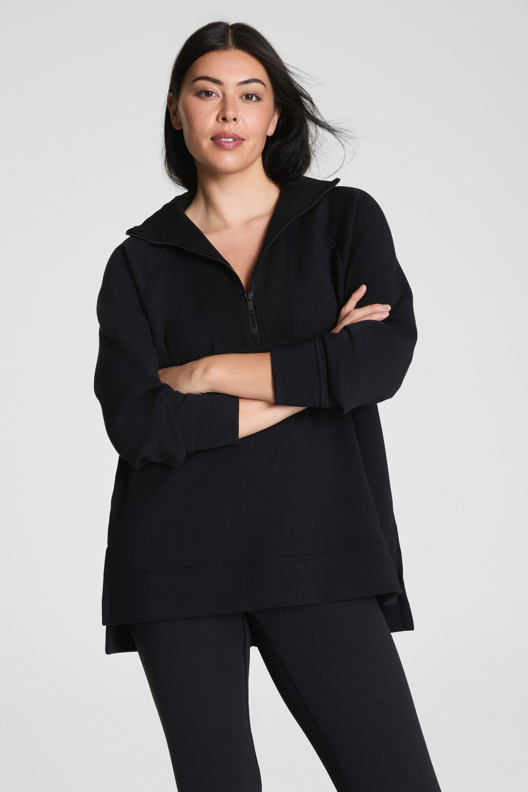 Woman wearing a black outfit with a quarter zip on a white background