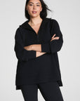 Woman wearing a black outfit with a quarter zip on a white background