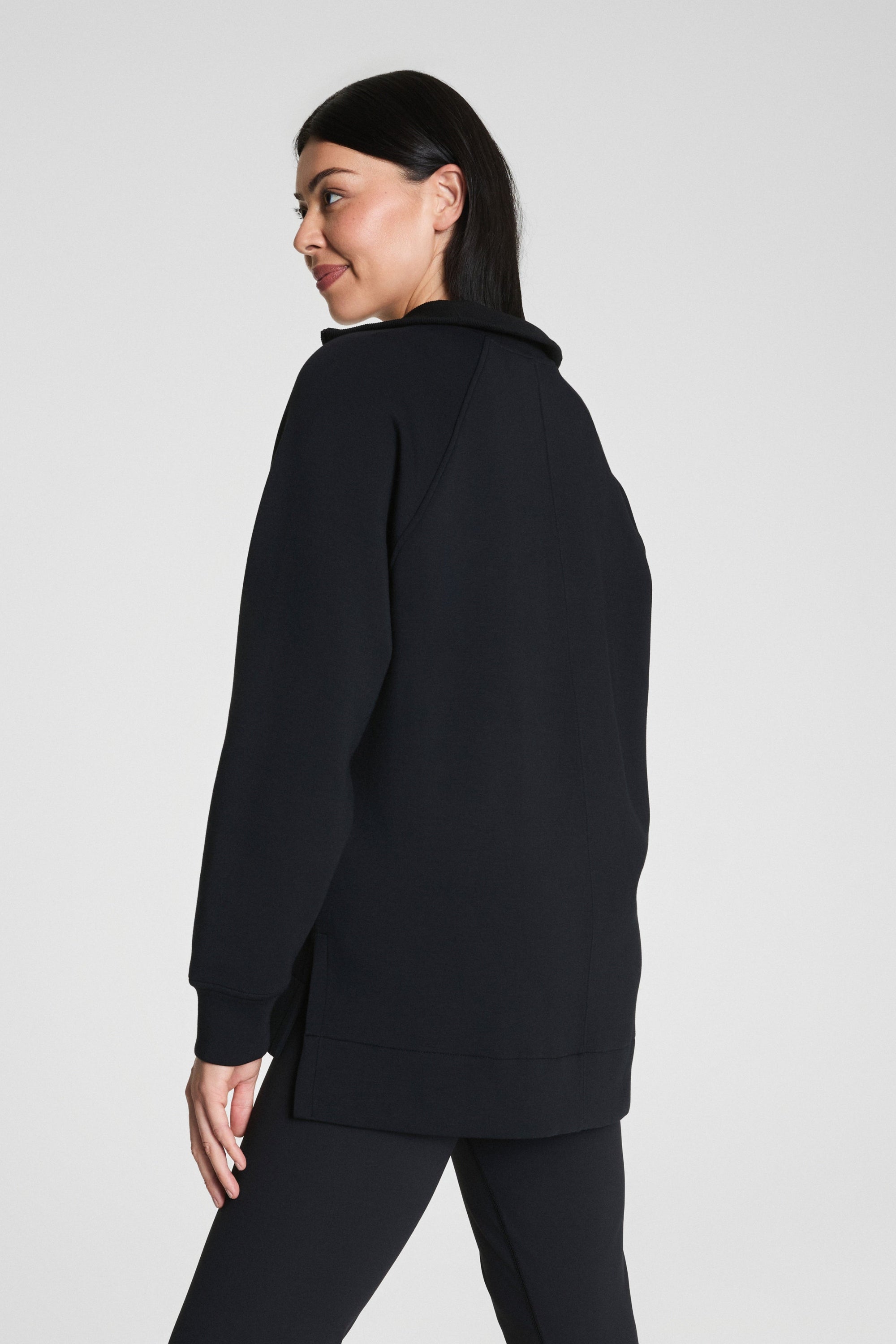 Person wearing a black hoodie and pants on a light gray background