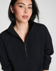Woman wearing a black quarter-zip sweatshirt against a plain background