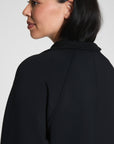 Woman wearing a black blazer against a plain background