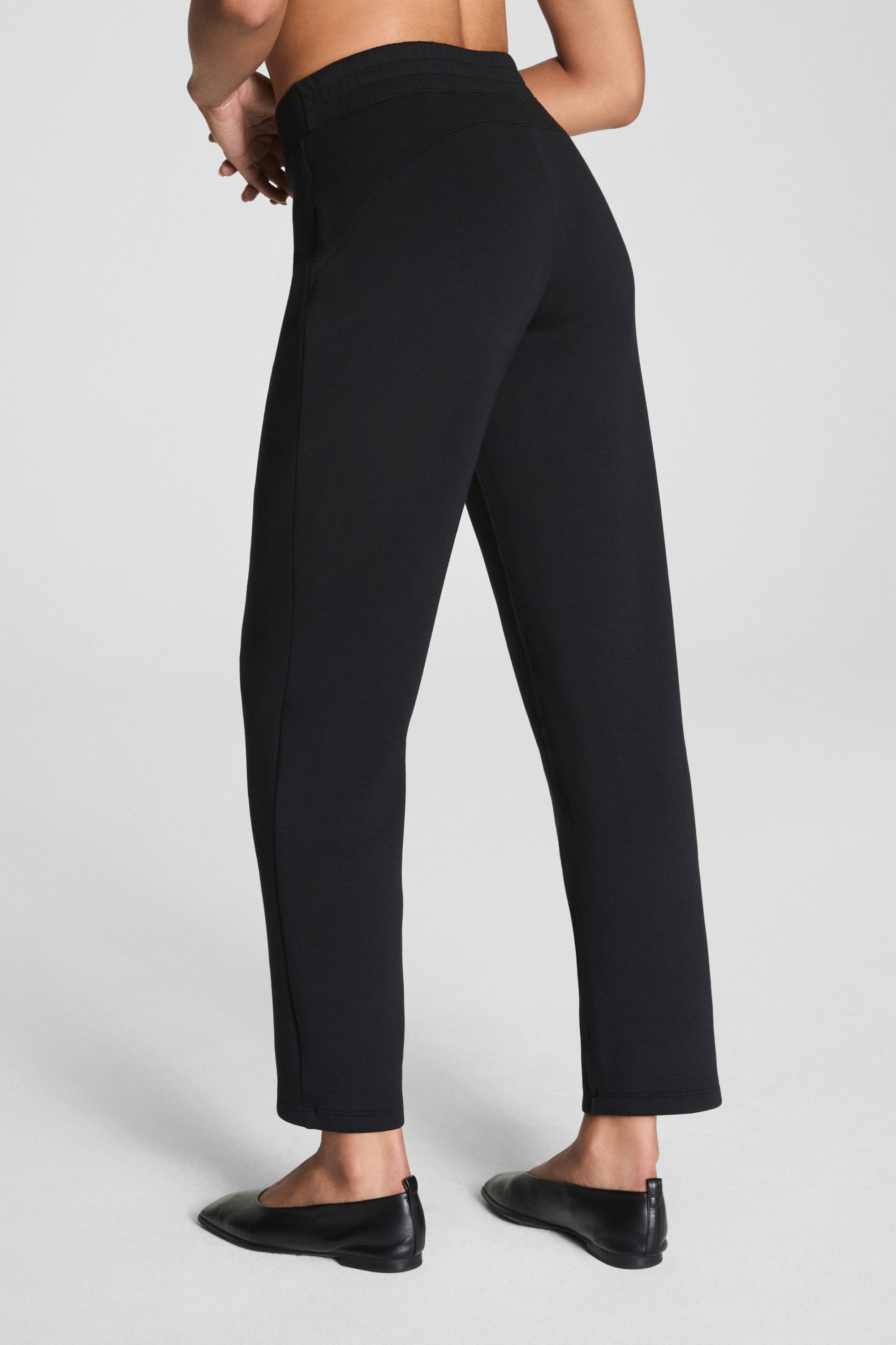 Person wearing black pants on a light gray background