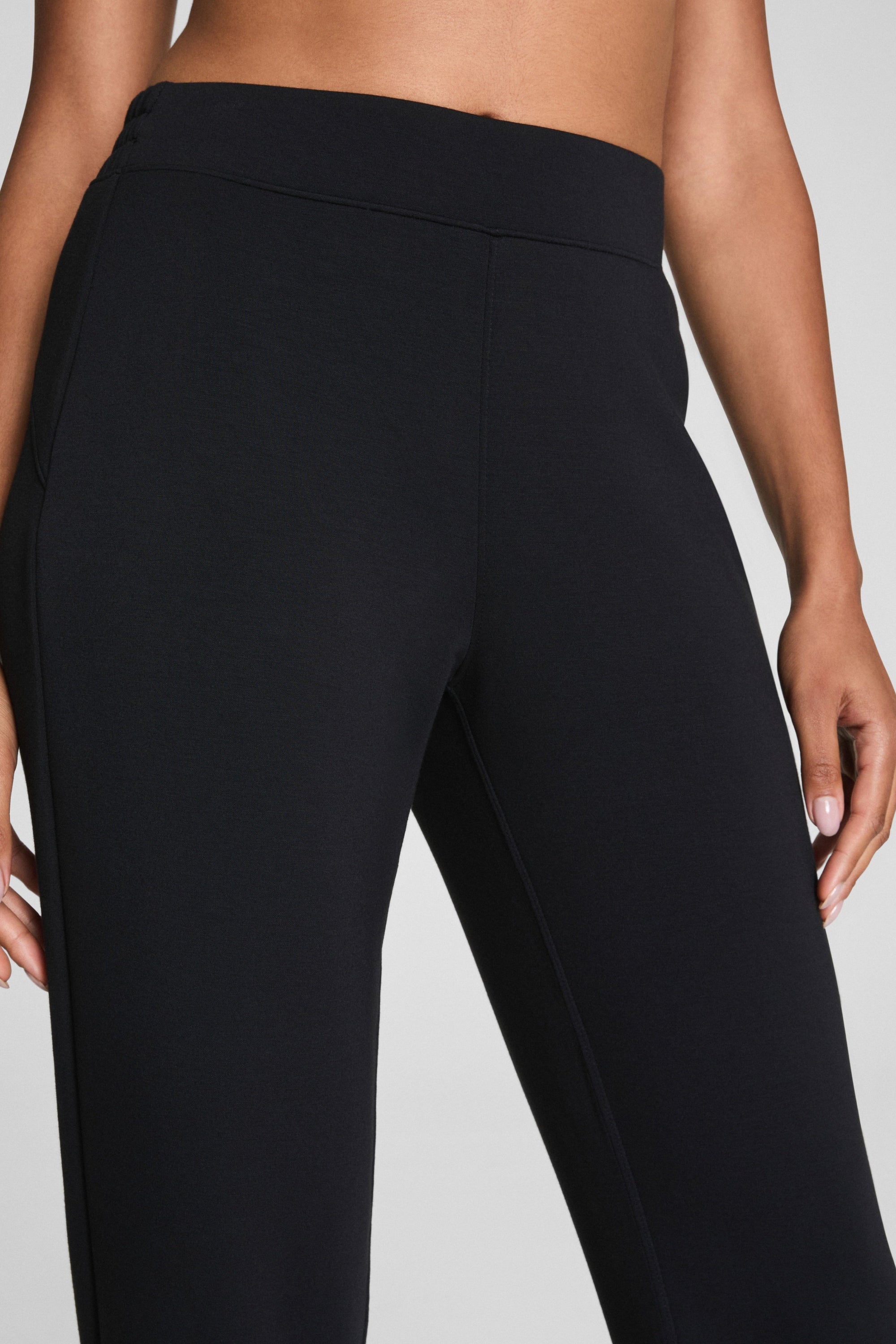 Black high-waisted leggings worn by a person on a gray background