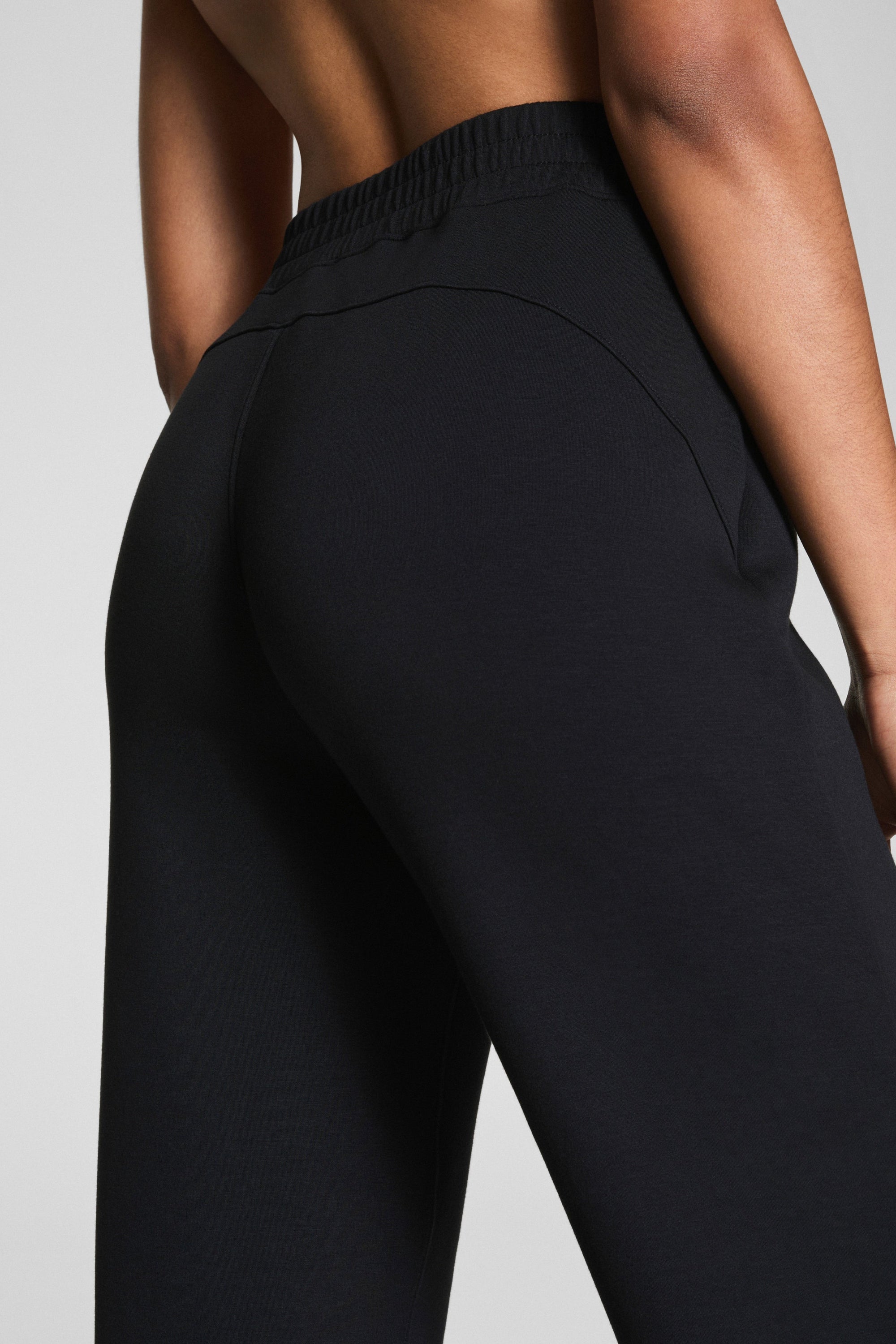 Black high-waisted pants worn by a person on a light gray background
