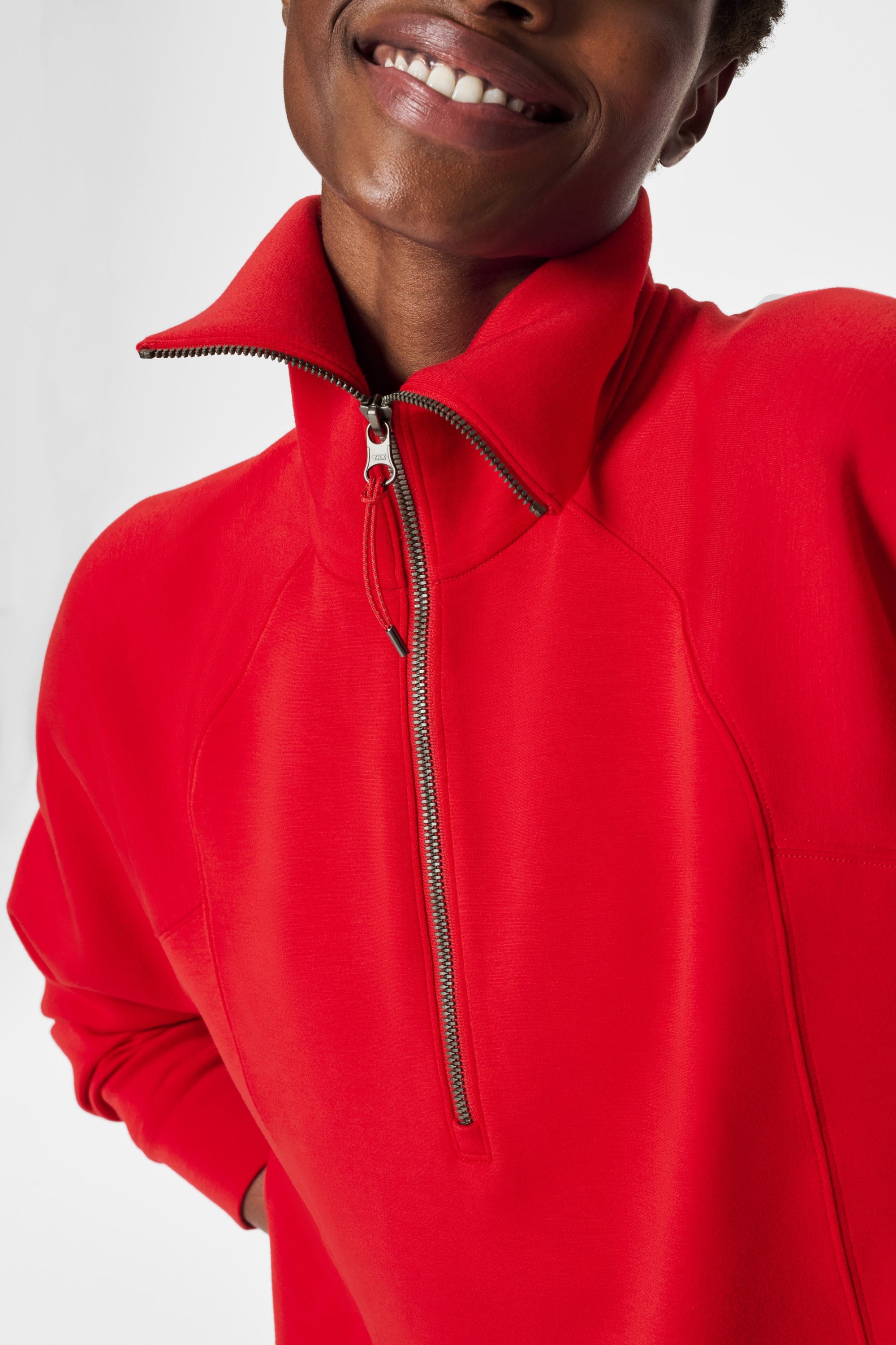 Person wearing a red quarter-zip sweatshirt on a light gray background
