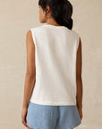 Woman wearing a white sleeveless top and blue shorts on a beige background