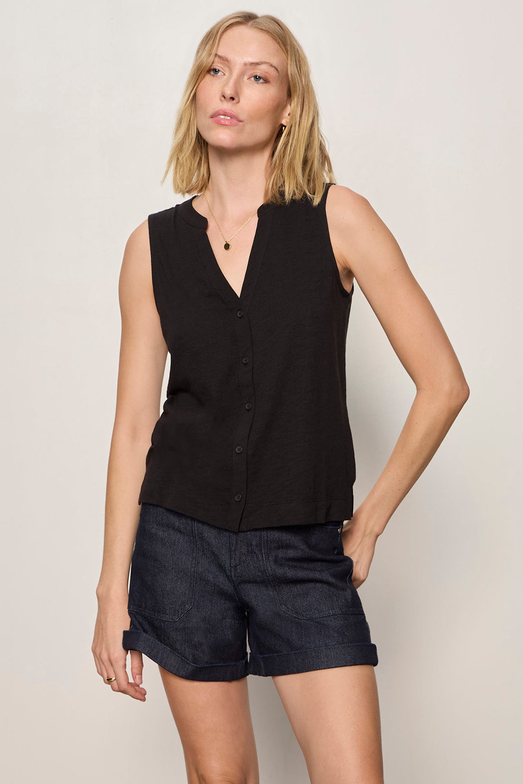 Woman wearing a black sleeveless top and shorts on a plain background