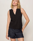 Woman wearing a black sleeveless top and shorts on a plain background