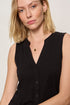 Woman wearing a black sleeveless top against a plain background