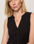 Woman wearing a black sleeveless top against a plain background