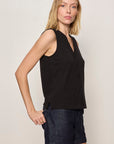 Woman wearing a black sleeveless top and dark shorts against a plain background