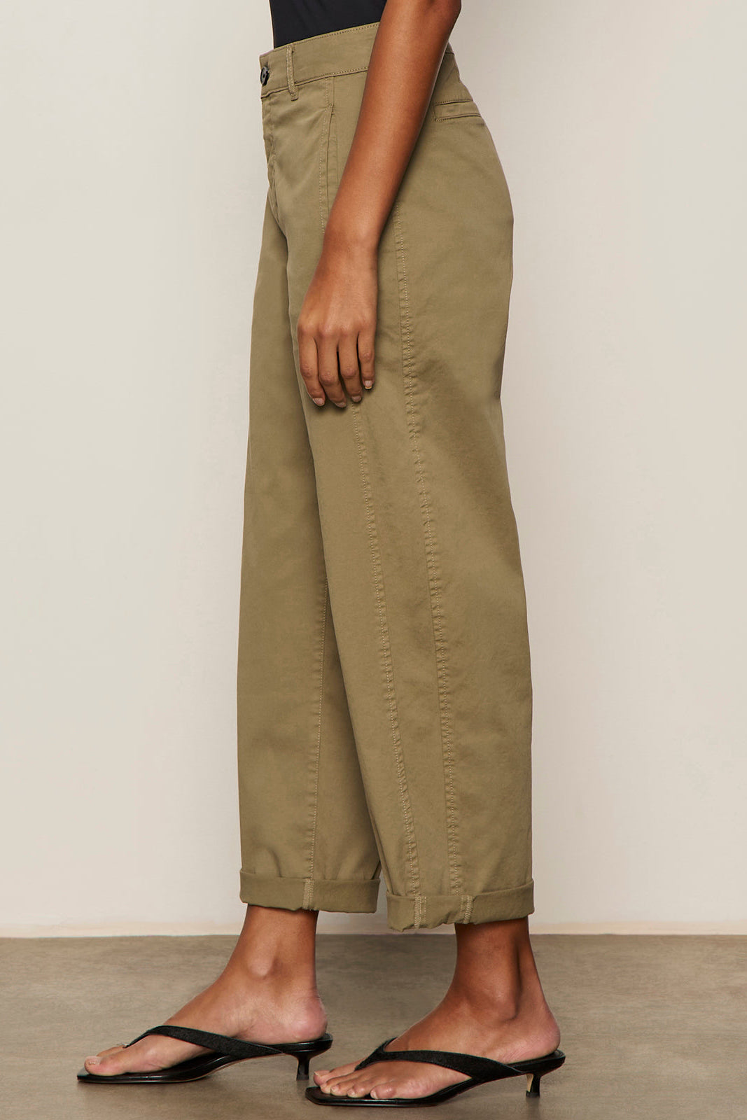 Person wearing olive green pants with a neutral background