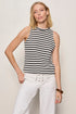 Woman wearing a black and white striped sleeveless top and white pants against a plain background