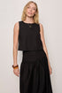 Woman wearing a black sleeveless top and skirt against a plain background
