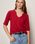 Woman wearing a red shirt and blue jeans against a plain background