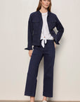 Woman wearing a navy jacket and pants with a white shirt, standing against a plain background.