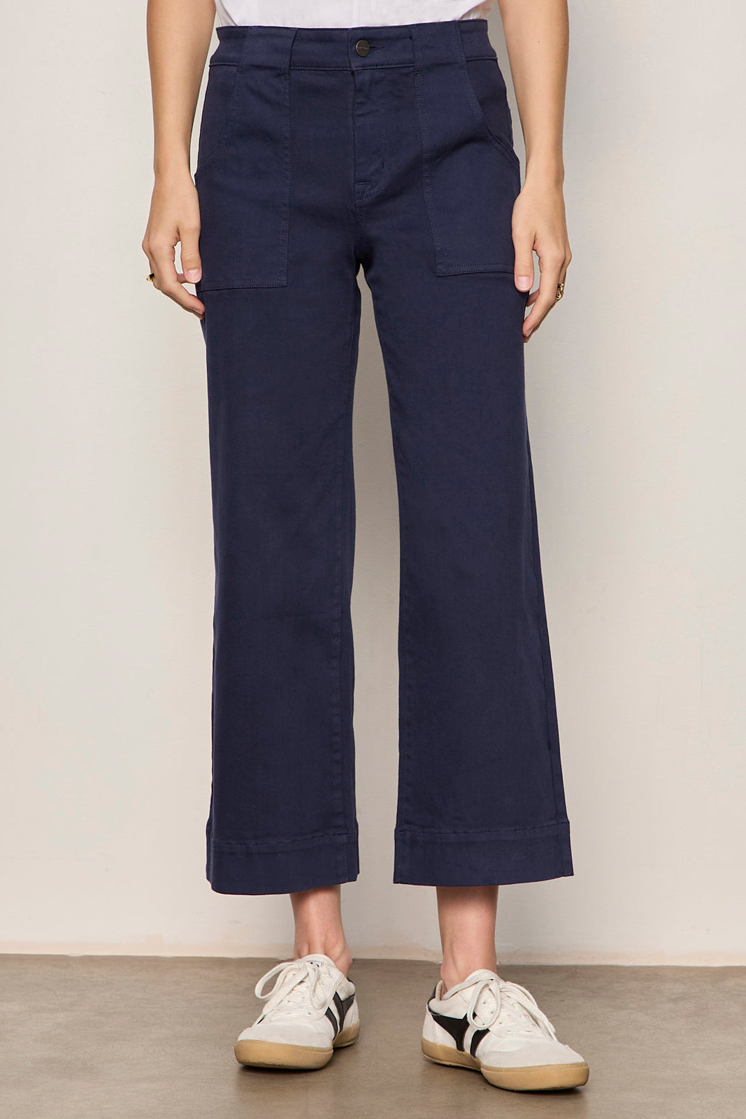 Person wearing navy blue pants with a plain background