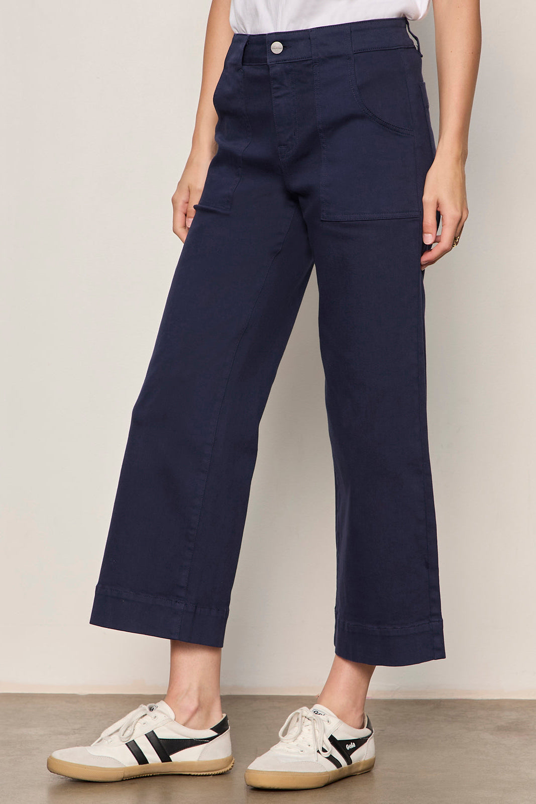 Person wearing navy blue pants with a plain background