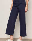 Person wearing navy blue pants with a plain background