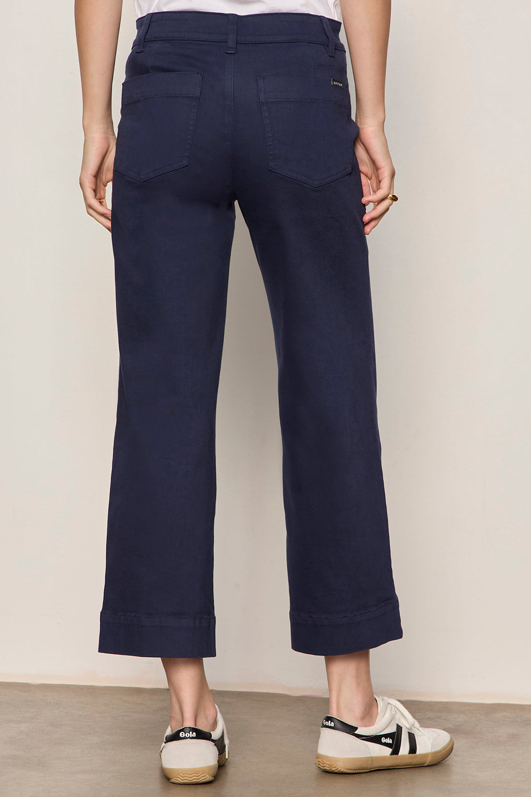 Navy blue pants worn by a person on a plain background