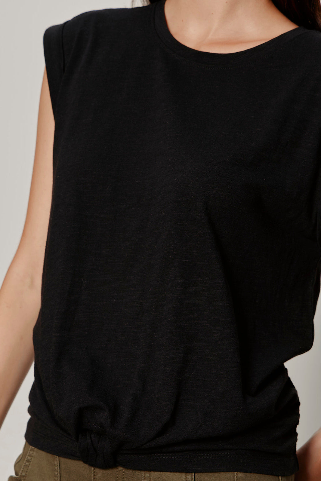 Black sleeveless top worn by a person on a neutral background