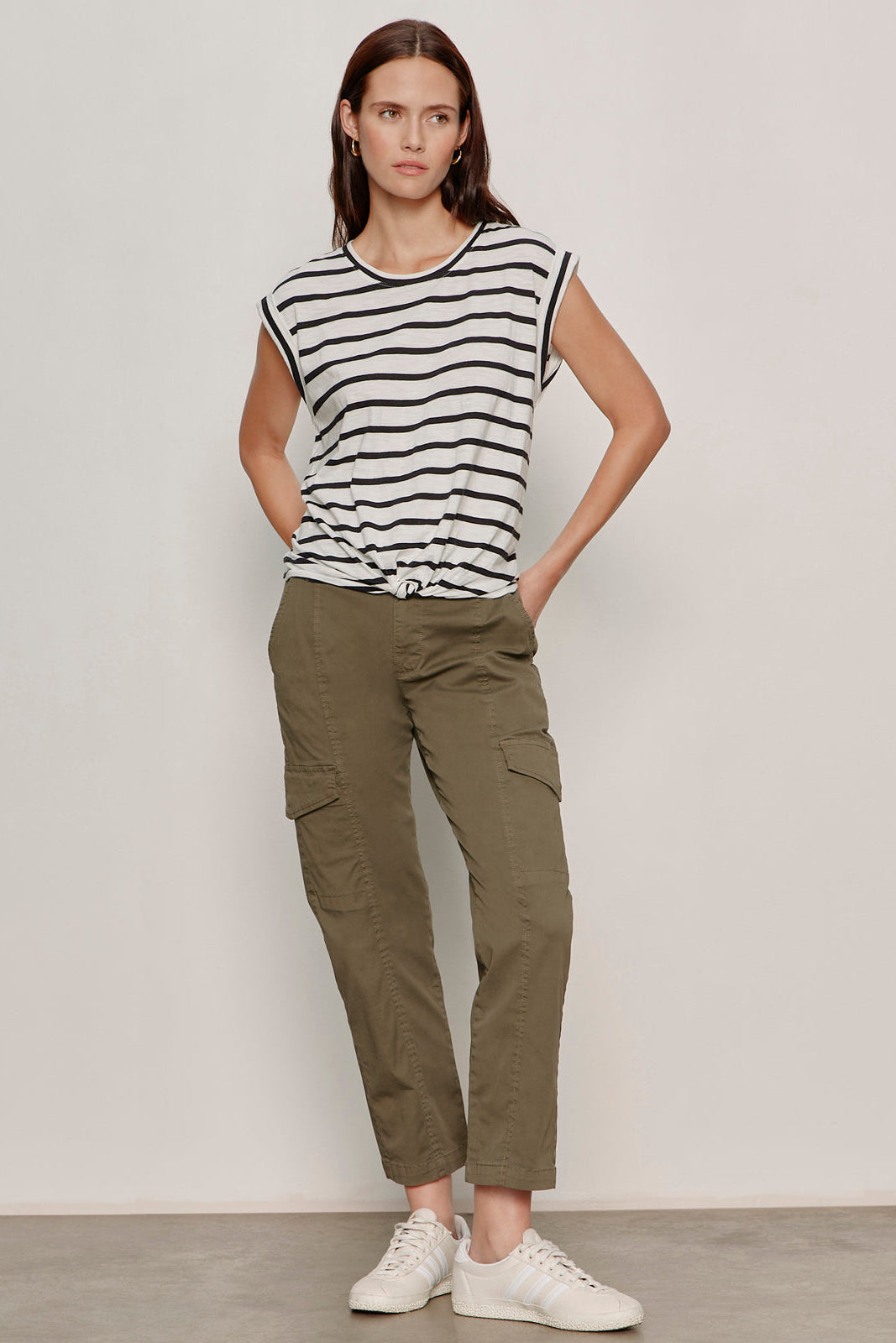 Woman wearing a striped shirt and cargo pants against a plain background