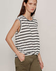 Woman wearing a black and white striped sleeveless top and green cargo pants on a plain background