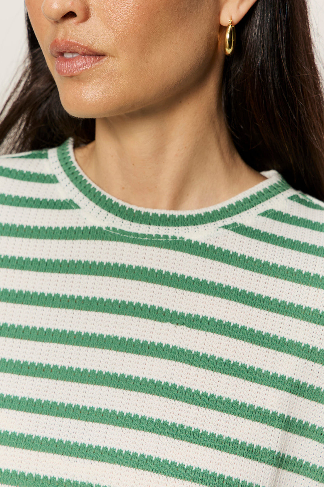 Close-up of a person wearing a green and white striped shirt with a neutral background