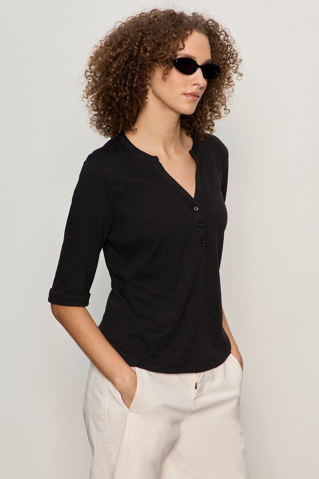 Woman wearing a black shirt and sunglasses against a plain background