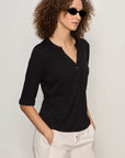 Woman wearing a black shirt and sunglasses against a plain background