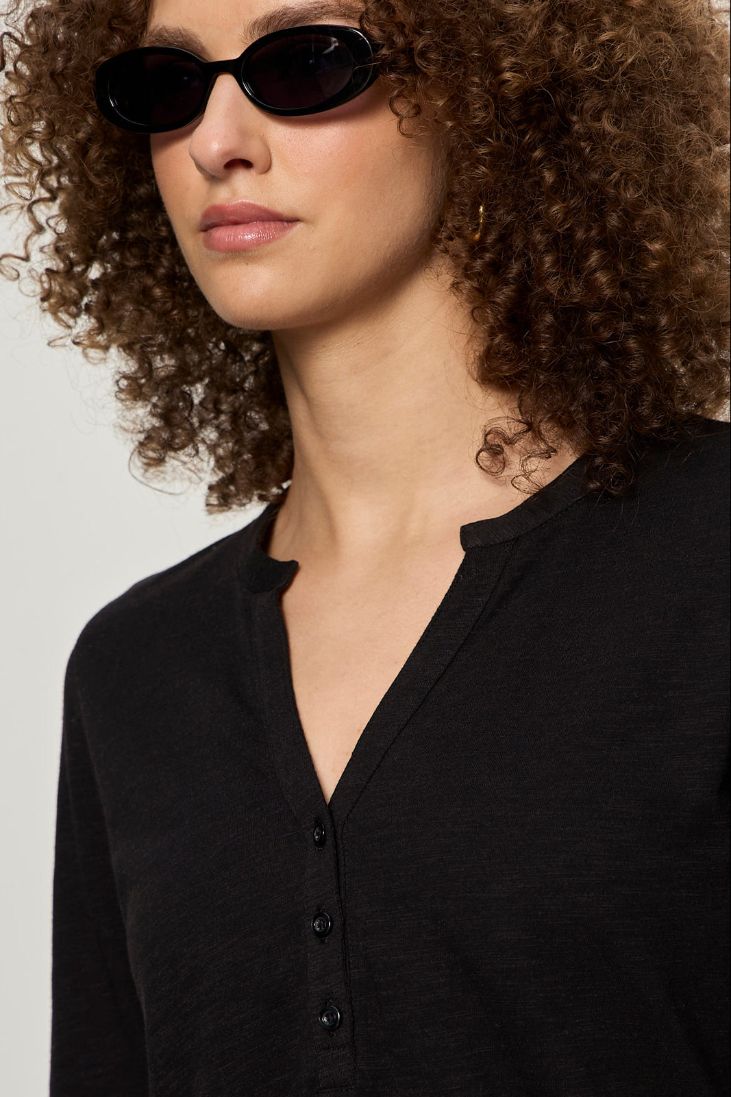 Person wearing a black shirt and sunglasses with a neutral background