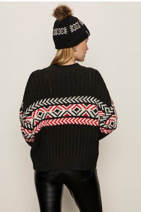 Person wearing a black sweater with a colorful pattern and a matching beanie on a white background