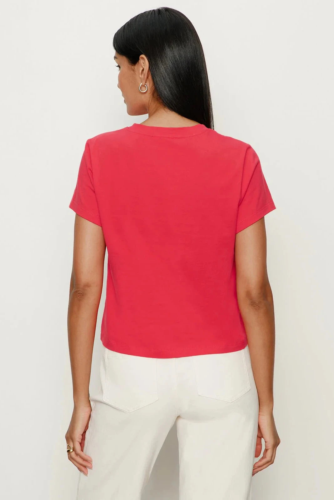 Person wearing a red t-shirt and white pants on a plain background