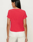 Person wearing a red t-shirt and white pants on a plain background