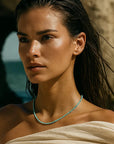 Woman with a necklace and draped garment against a natural background