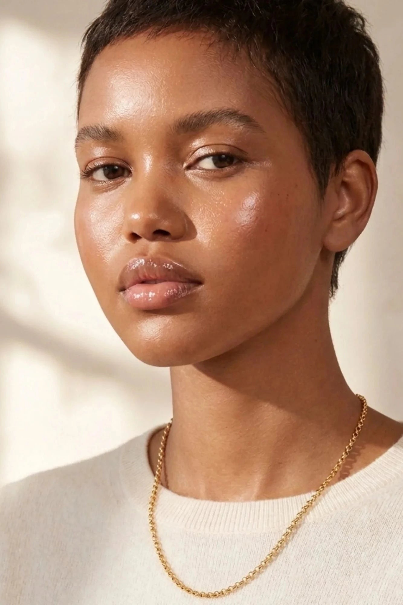Woman wearing a gold necklace against a neutral background