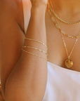 Close-up of a person wearing multiple gold necklaces and an arm band.