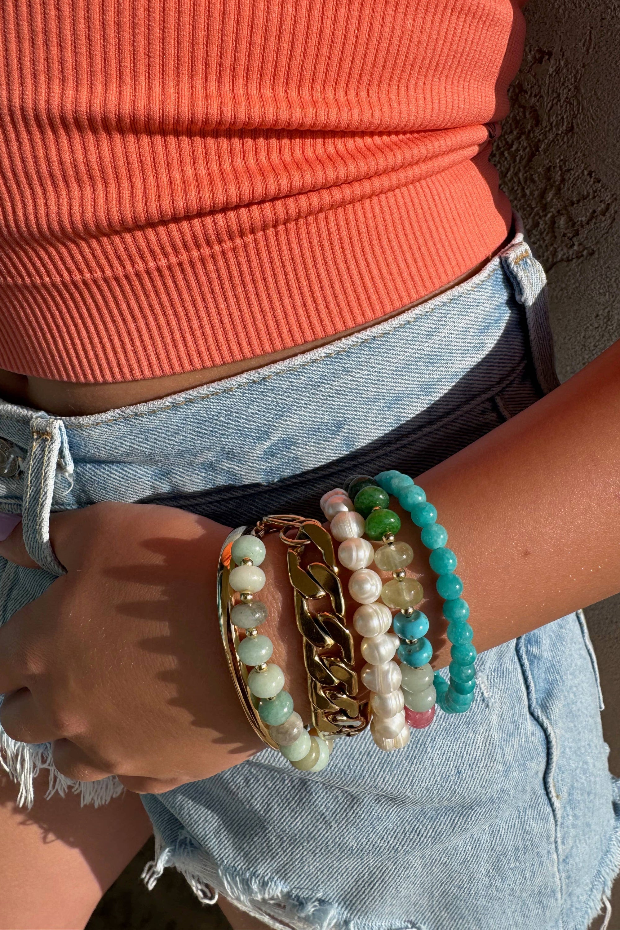 Person wearing multiple bracelets on a wrist with a blurred background