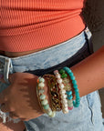 Person wearing multiple bracelets on a wrist with a blurred background