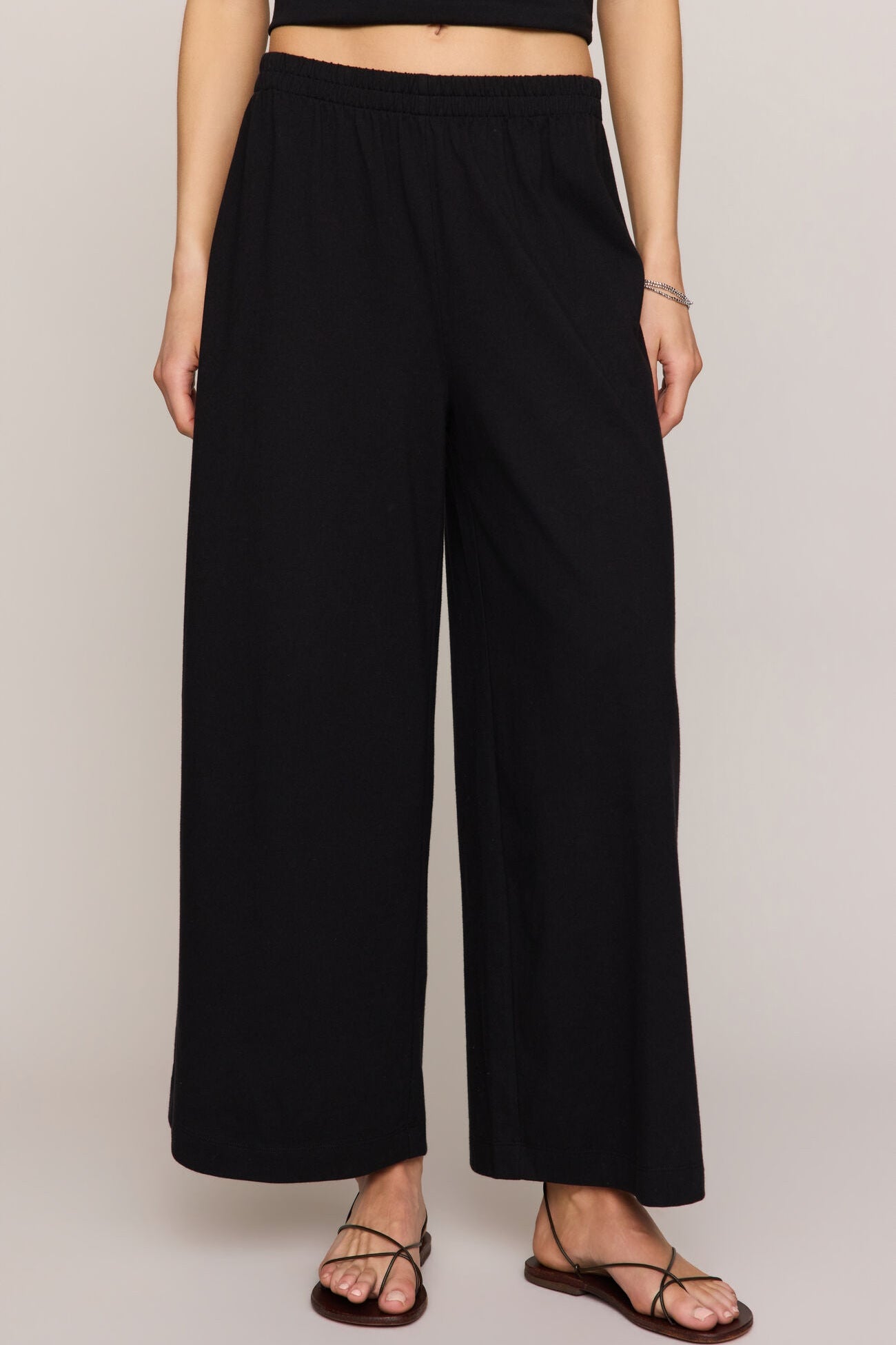 Person wearing black wide-leg pants on a plain background