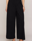 Person wearing black wide-leg pants on a plain background