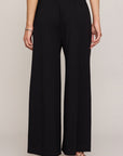 Person wearing black wide-leg pants on a plain background