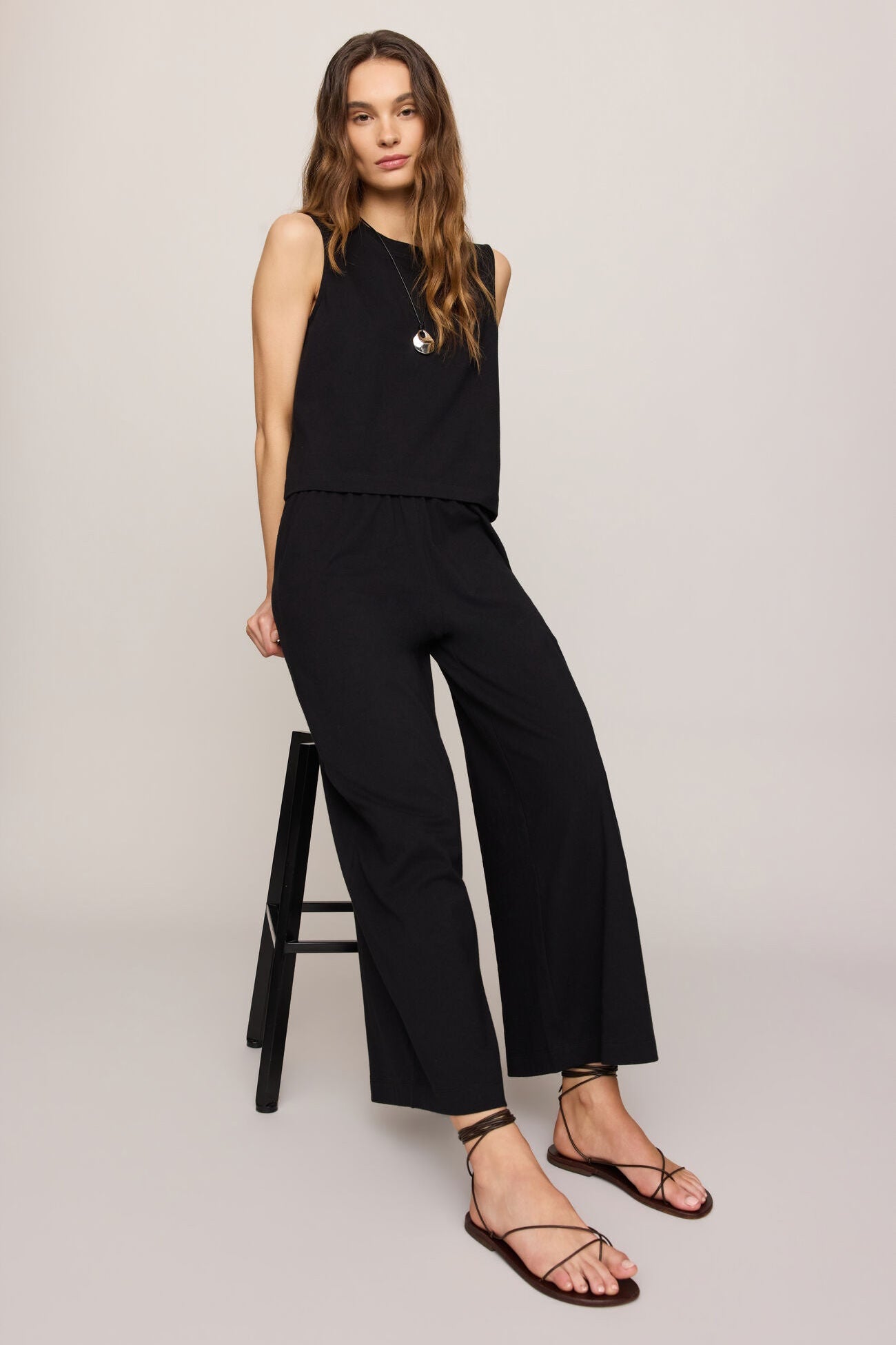 Woman wearing a black sleeveless top and pants on a white background