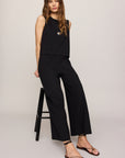 Woman wearing a black sleeveless top and pants on a white background