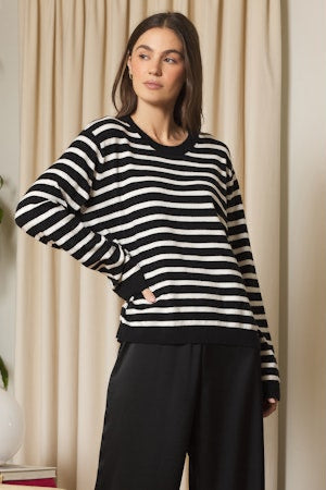 Woman wearing a black and white striped sweater with a neutral background