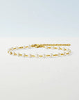 Gold chain bracelet with pearls on a white background