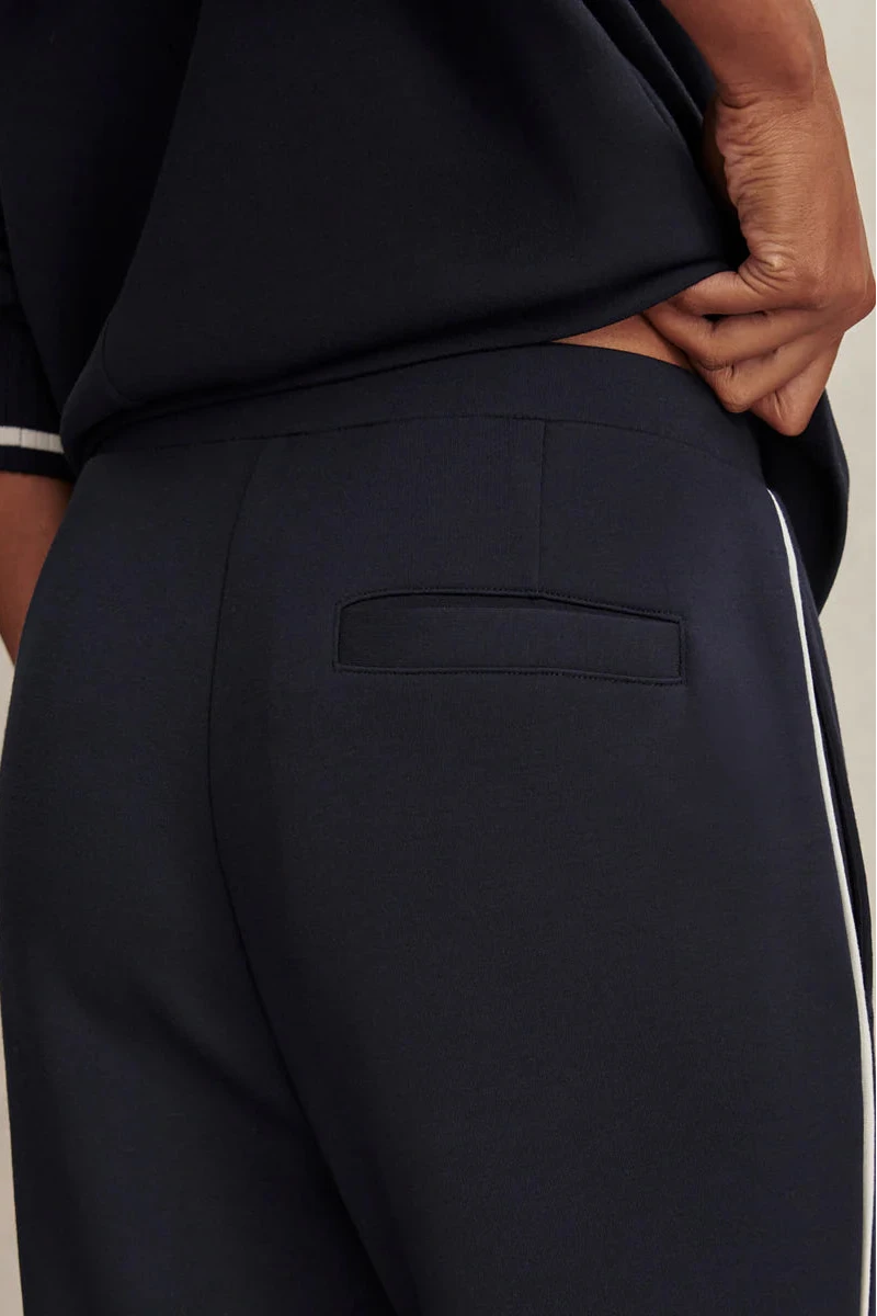 Navy blue pants with a white stripe on a neutral background