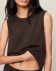 Woman wearing a brown sleeveless top and pants against a neutral background