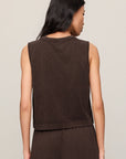 Woman wearing a brown sleeveless top and pants against a plain background