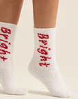 A pair of white plush socks with the word 'BRIGHT' written in red on the side.
